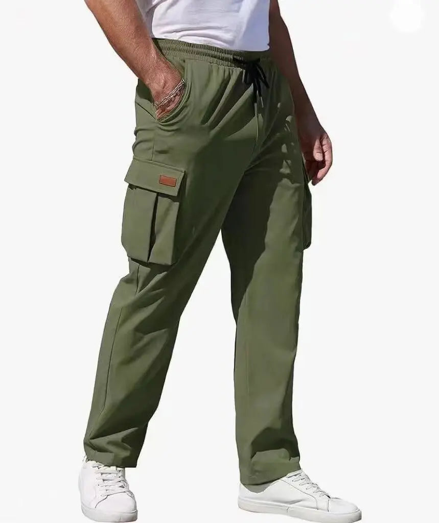 Man wearing loose fit olive green cargo pants with utility pockets and elastic waistband, styled with white sneakers and white tee for casual streetwear.